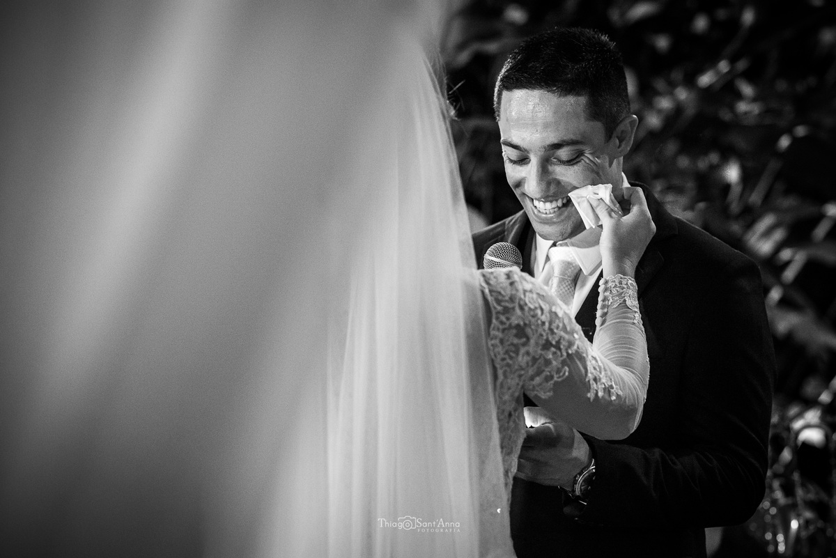 noiva seca as lágrimas do noivo que sorri enquanto lê seus votos preto e branco
