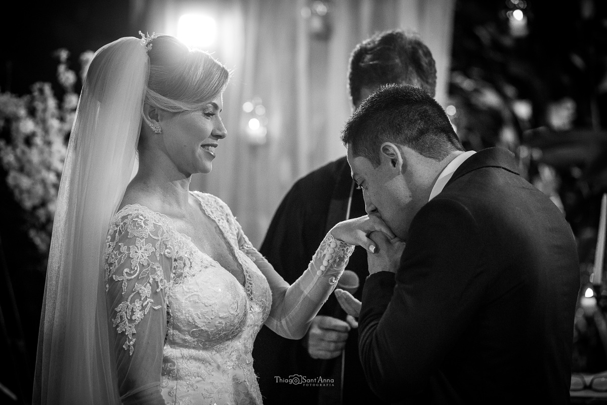 noivo beija a mão da noiva durante a cerimônia preto e branco