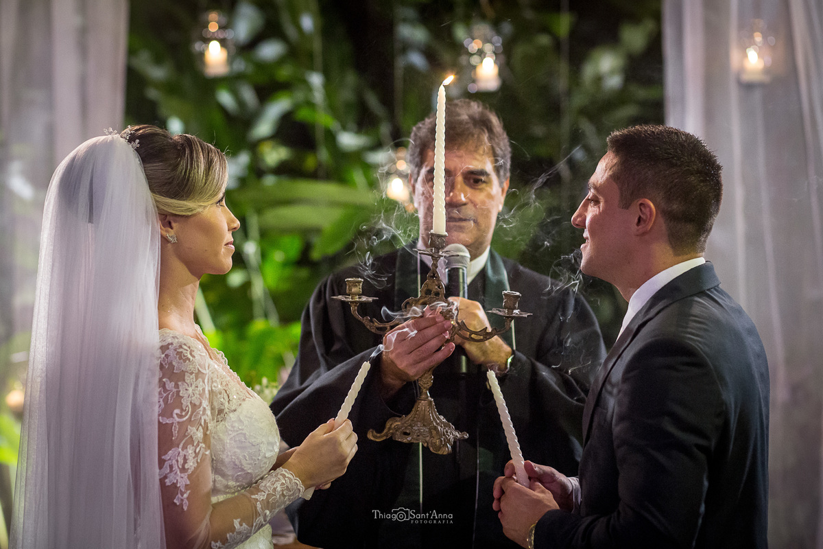 noivos acendem juntos uma vela junto ao padre cerimônia casamento