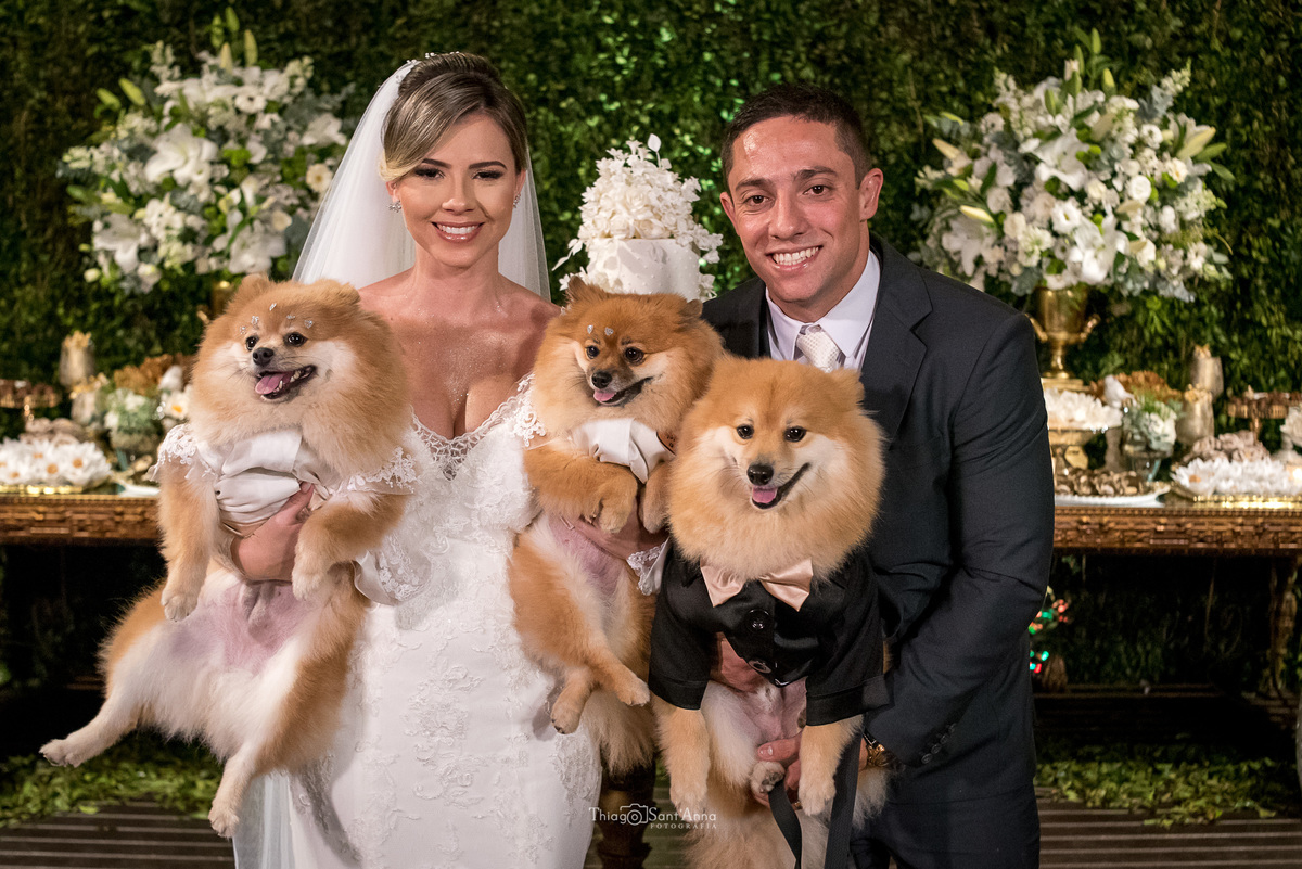 noivos sorrindo seguram seus pets decoração dourado flores brancas