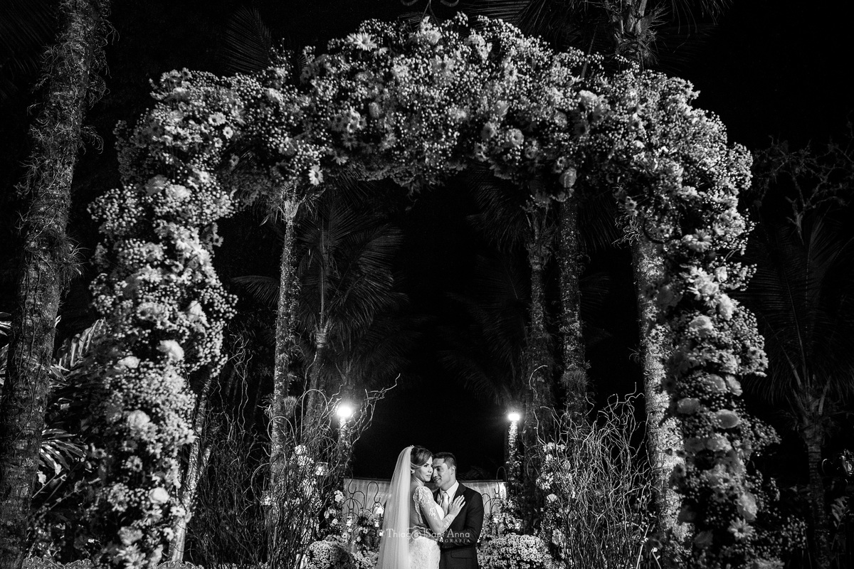 noivos sob arco de flores preto e branco 