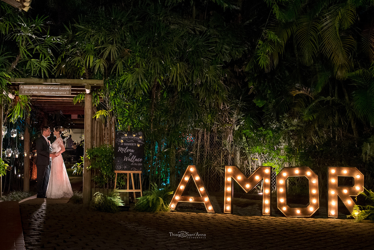 noivos se abraçam ao lado de letreiro luminoso parede viva