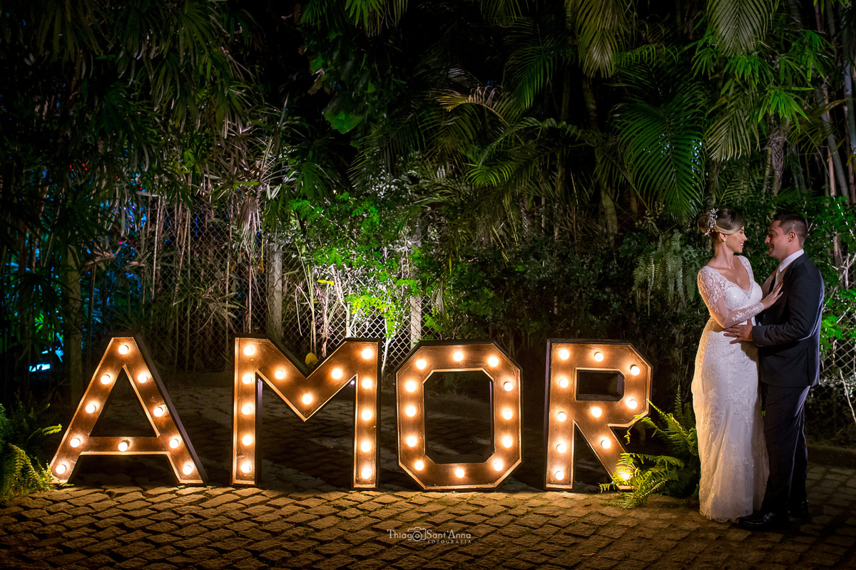 noivos se abraçam ao lado de letreiro luminoso parede viva