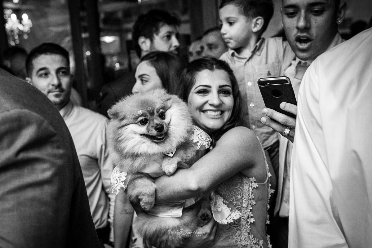 madrinha sorri dançando com pet dos noivos padrinhos ao fundo