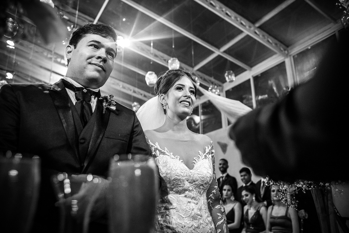 casamento cerimônia noivos ouvem o pastor convidados ao fundo decoração luminárias no teto 