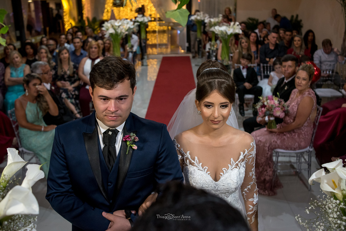 casamento cerimônia noivos ouvem o pastor decoração flores copo de leite convidados ao fundo 