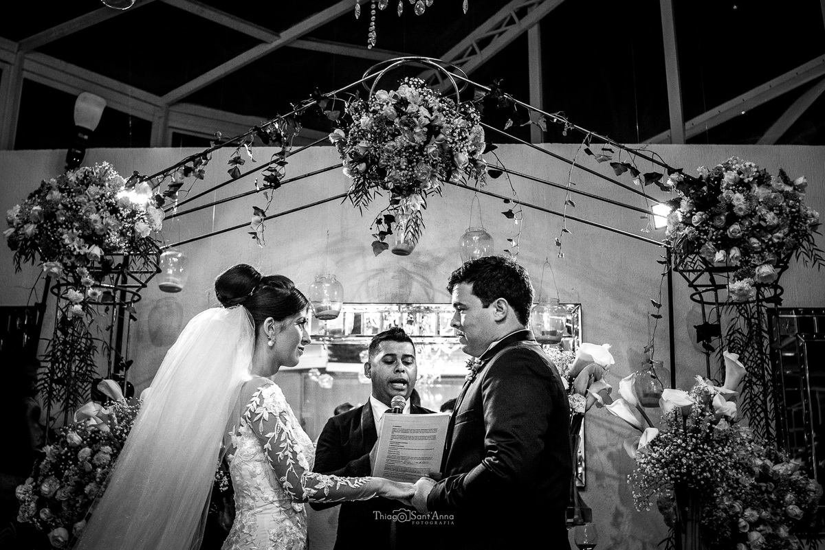 casamento cerimônia noivos ouvem o pastor decoração estrutura metálica coberta por flores preto e branco