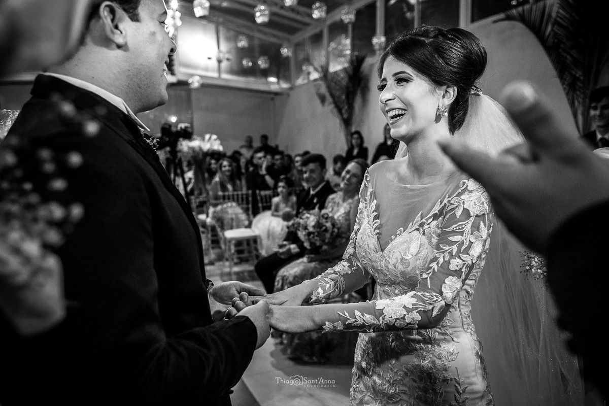 casamento cerimônia noivos ouvem o pastor decoração luminárias no teto noiva sorri 