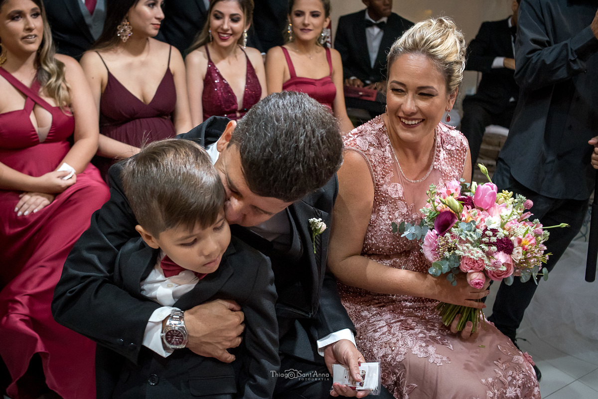 madrinhas vestido bordô padrinho beija criança mulher segura buque 