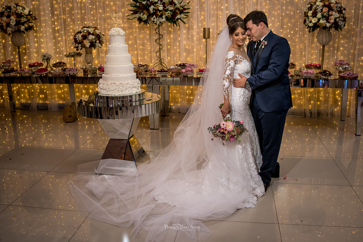 noivos se abraçam noiva vestido véu noivos se abraçam noiva véu buque tons de rosa noivo terno azul decoração flores coloridas tons de rosa bolo de casamento branco seis andares