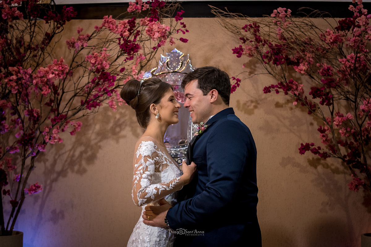 noivos se abraçam entre flores cor de rosa 