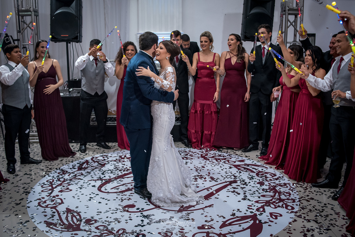 noivos dançam valsa noiva sorri padrinhos seguram bastões luminosos 