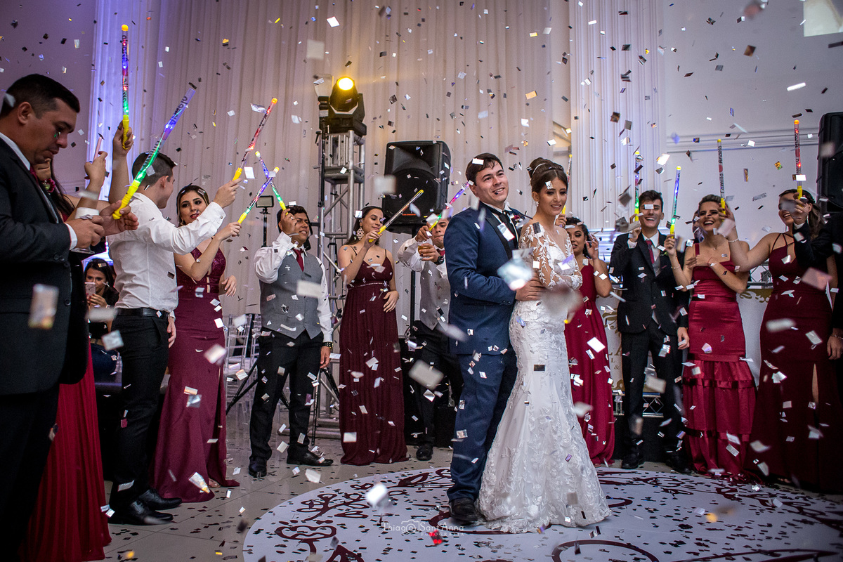 noivos dançam sob a queda do confete padrinhos em volta observam com bastões luminosos 