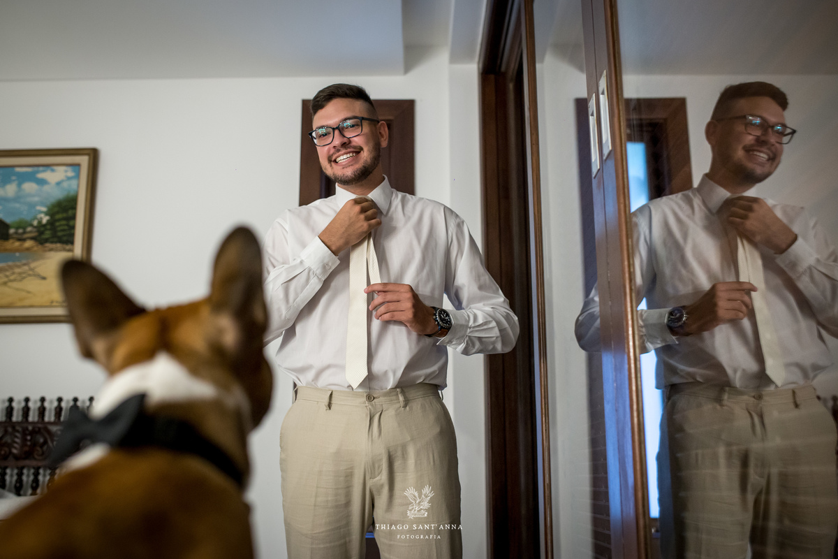 noivo ajusta sua gravata sorri observando seu pet 