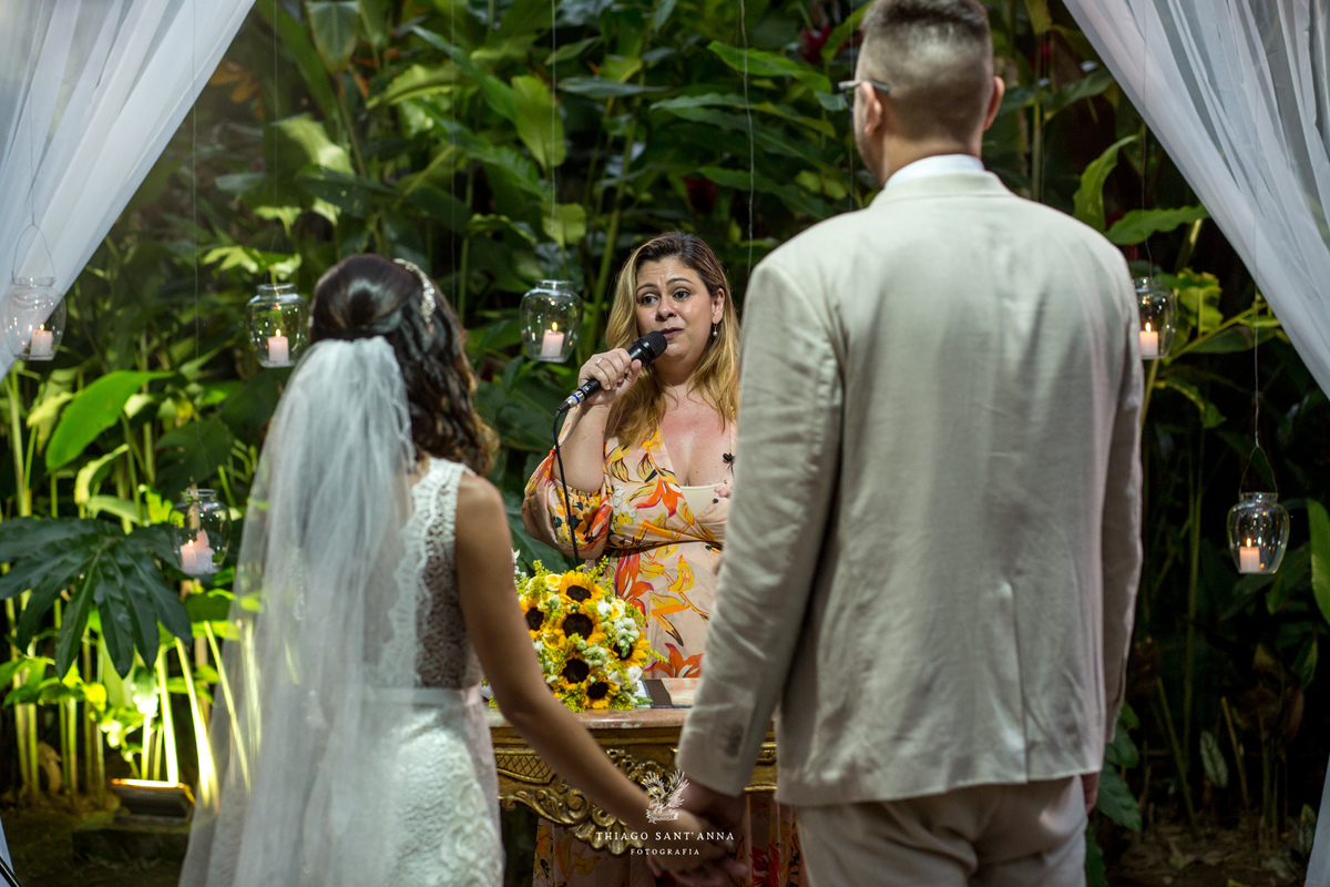 casal no altar de mãos dadas pastora fala ao microfone vegetação ao fundo 
