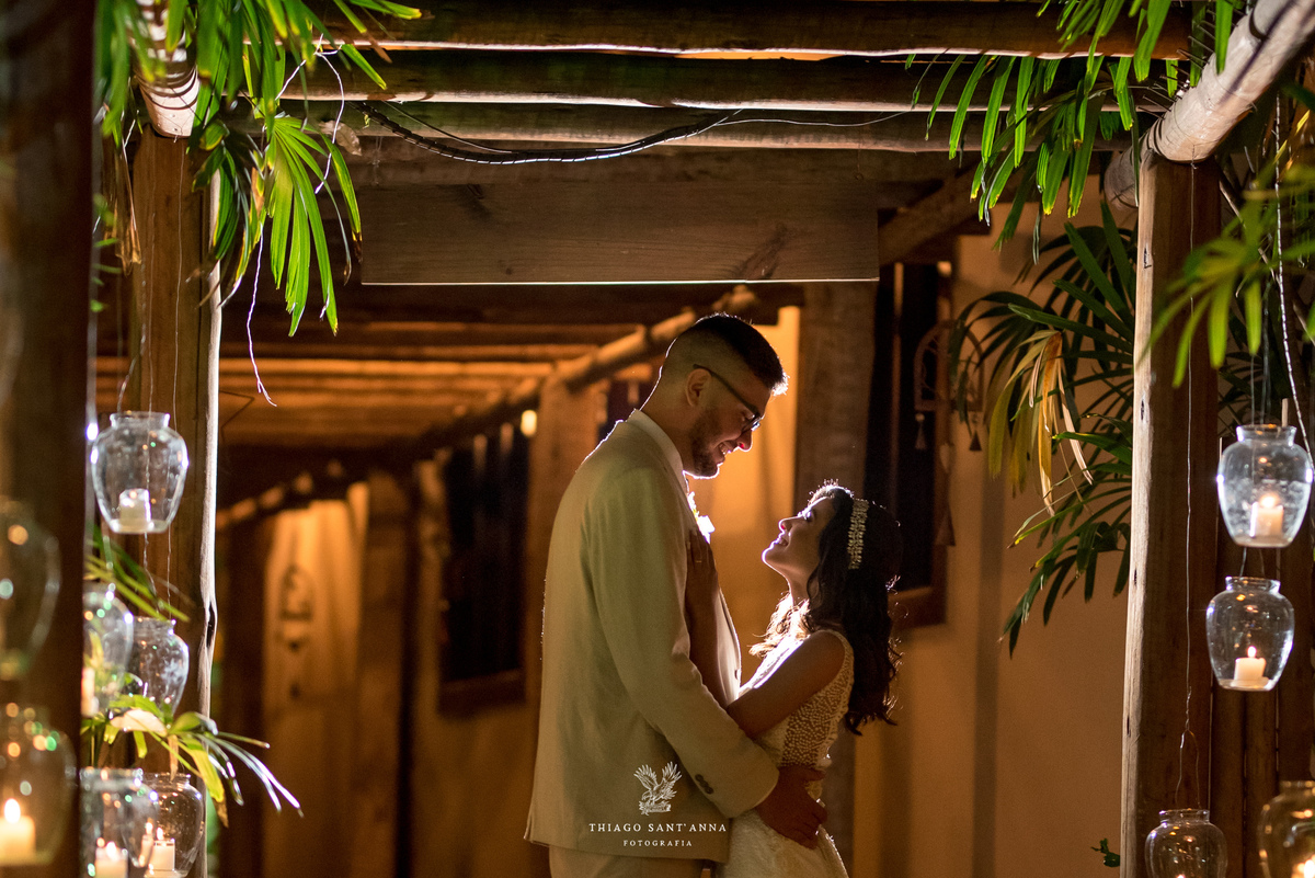 noivos posam abraçados caminho estrutura de madeira vegetação velas 