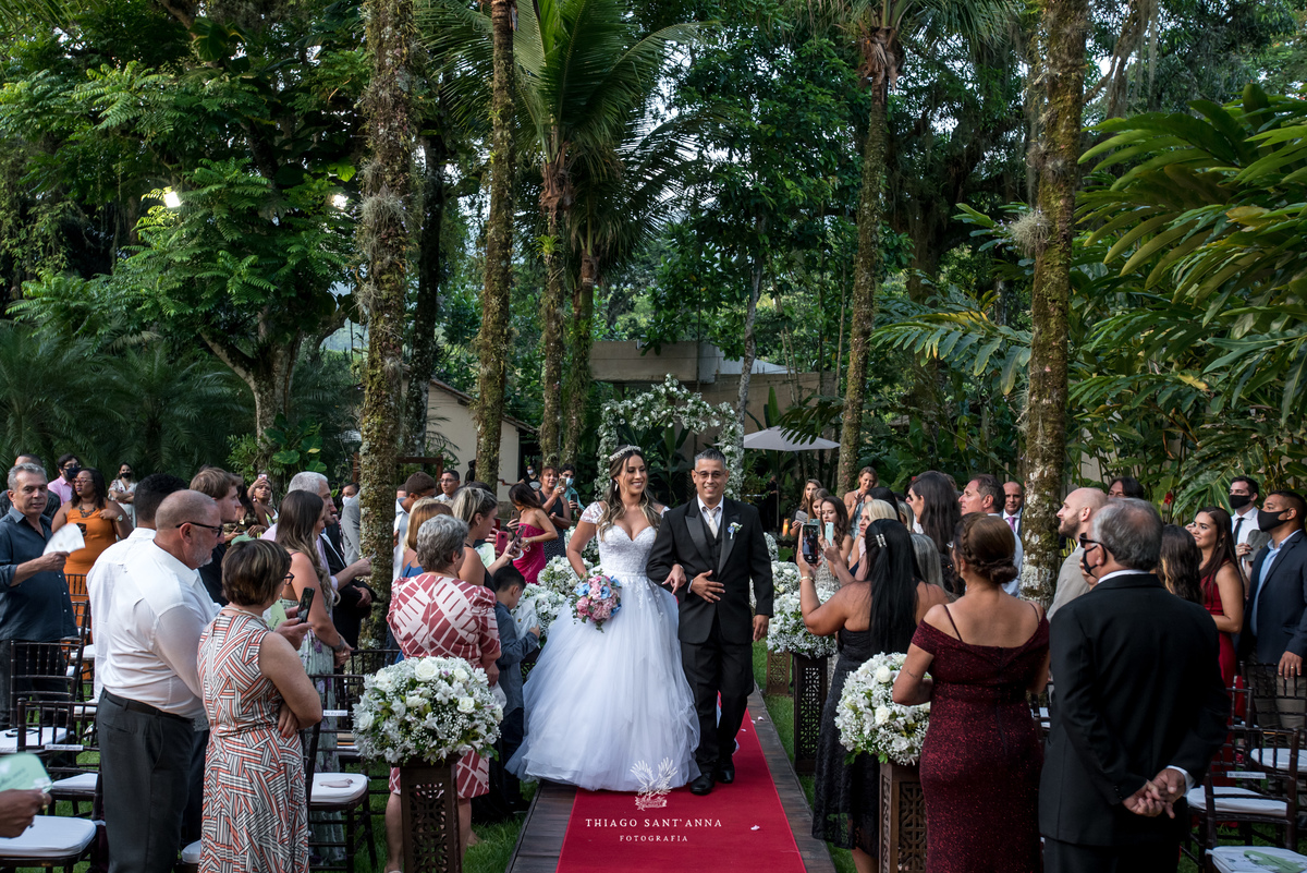 entrada da noiva com seu pai tapete vermelho decoração flores brancas convidados observam