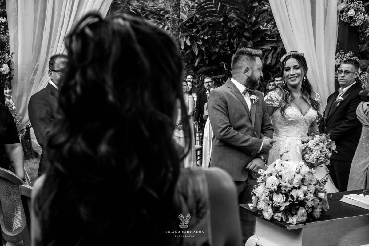 noivos no altar familiares observam flores preto e branco