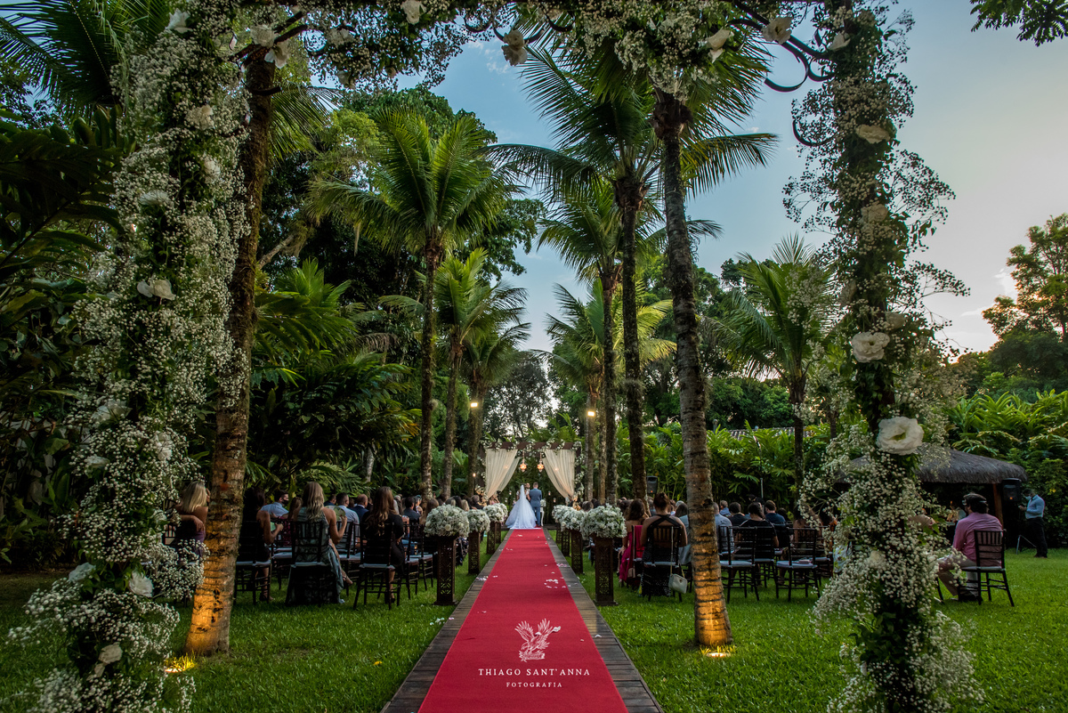 noivos no altar ambiente externo gramado coqueiros arco de flores brancas