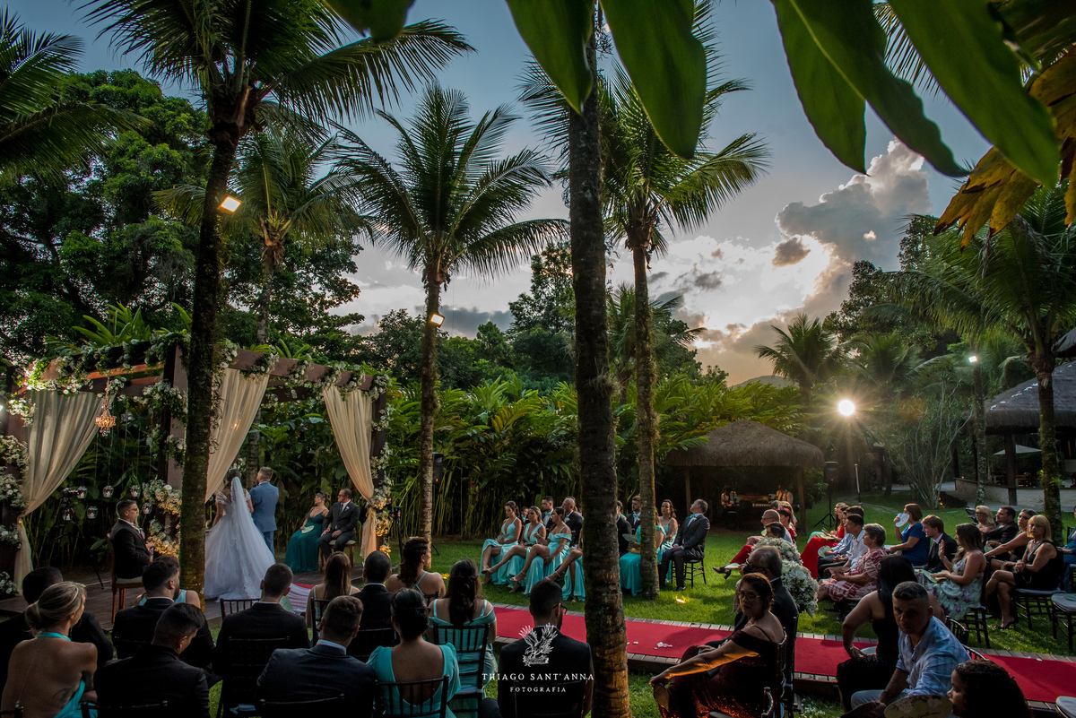 noivos no altar ambiente externo gramado coqueiros arco de flores brancas