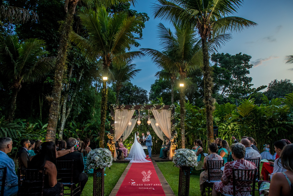 noivos no altar ambiente externo gramado coqueiros arco de flores brancas