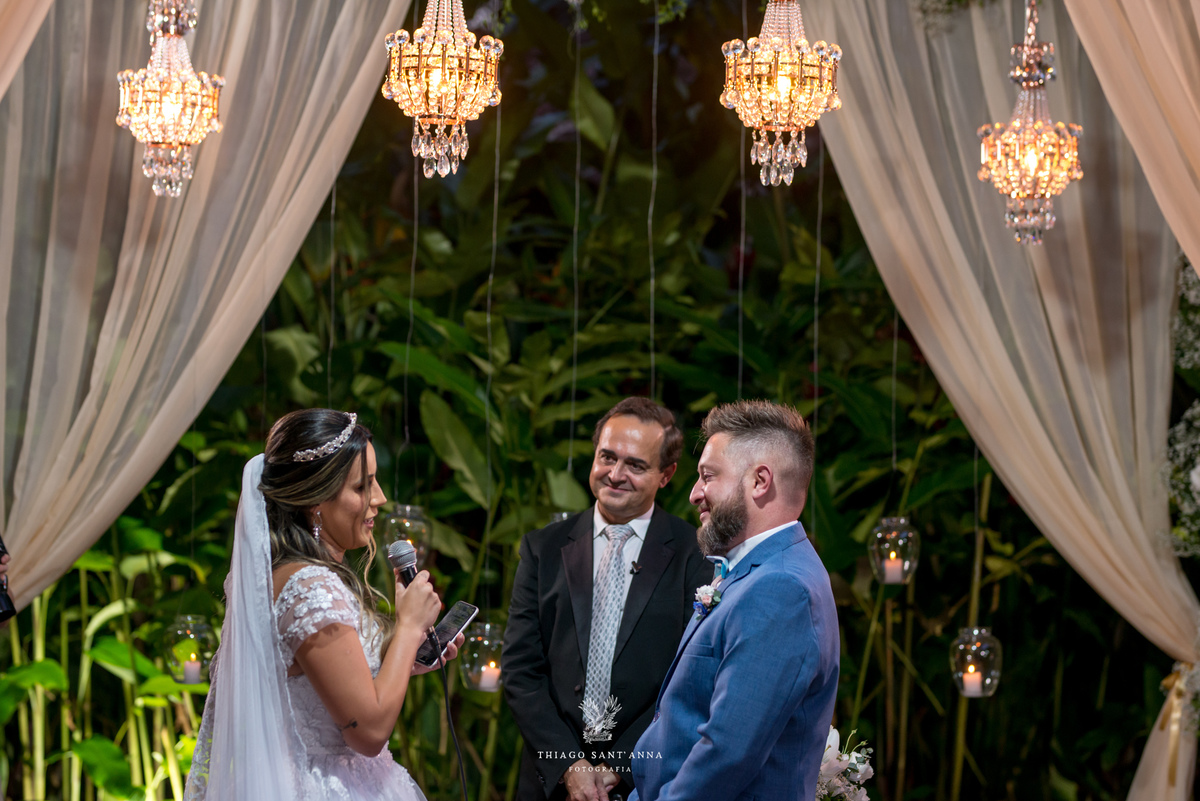 noivos no altar sorrindo noiva fala ao microfone decoração luminárias