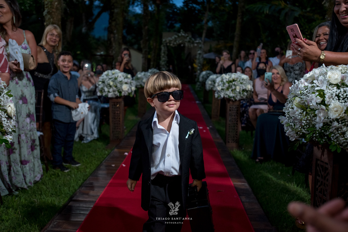 entrada do pajem de óculos escuros convidados observam decoração flores brancas