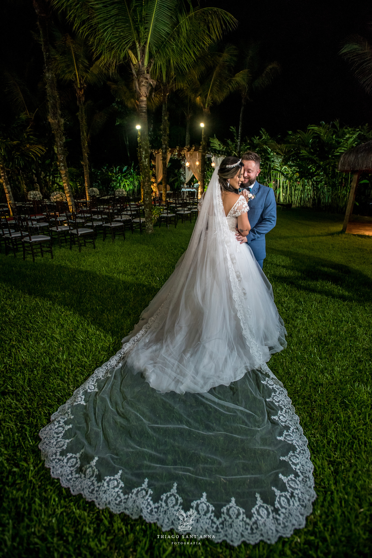 noivos abraçados ambiente externo vegetação flores brancas noivo terno azul noiva vestido renda 