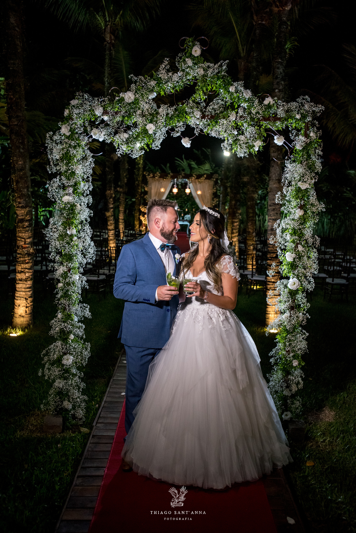 noivos brindam ambiente externo vegetação flores brancas noivo terno azul noiva vestido renda 