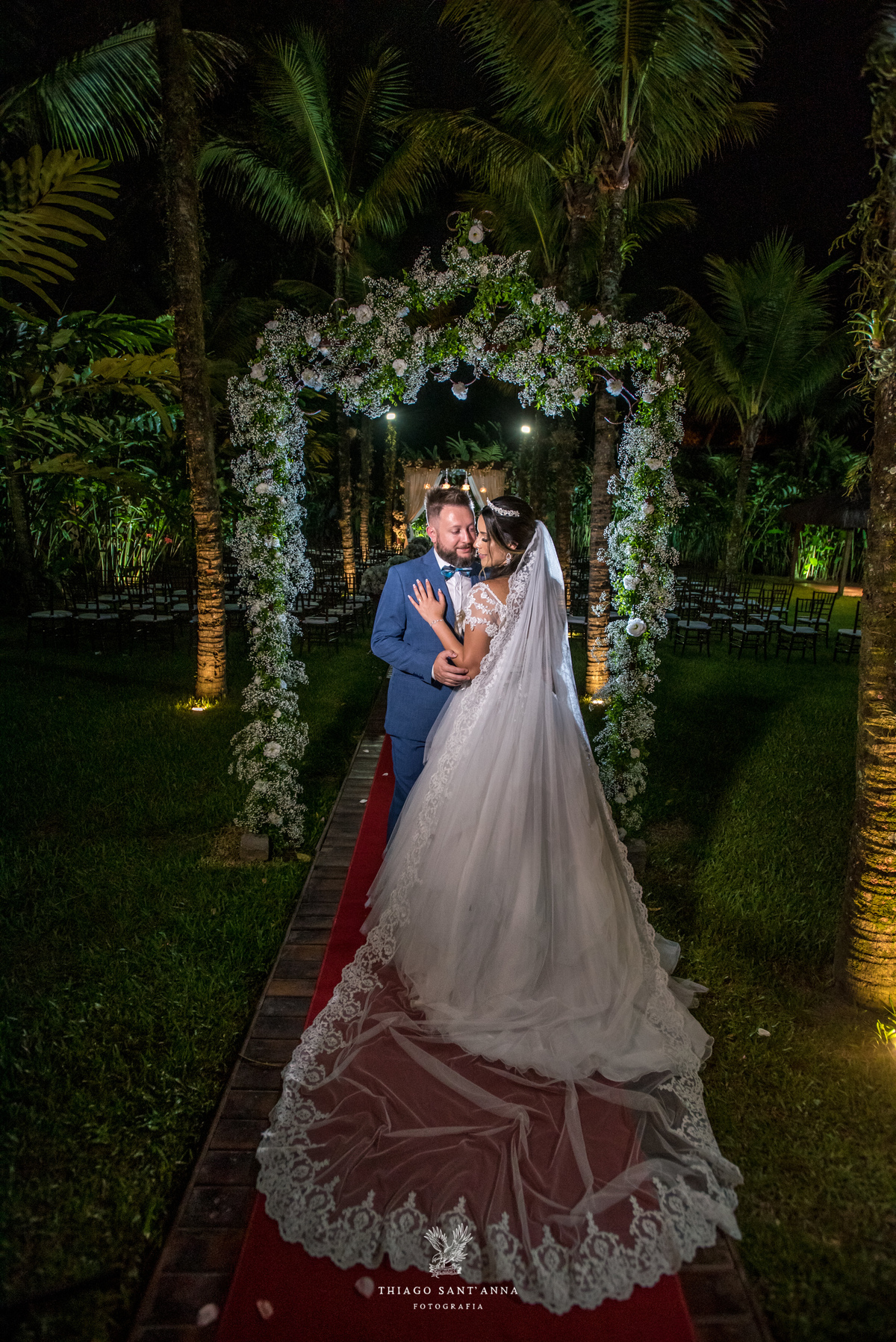 noivos se abraçam ambiente externo vegetação flores brancas noivo terno azul noiva vestido renda 