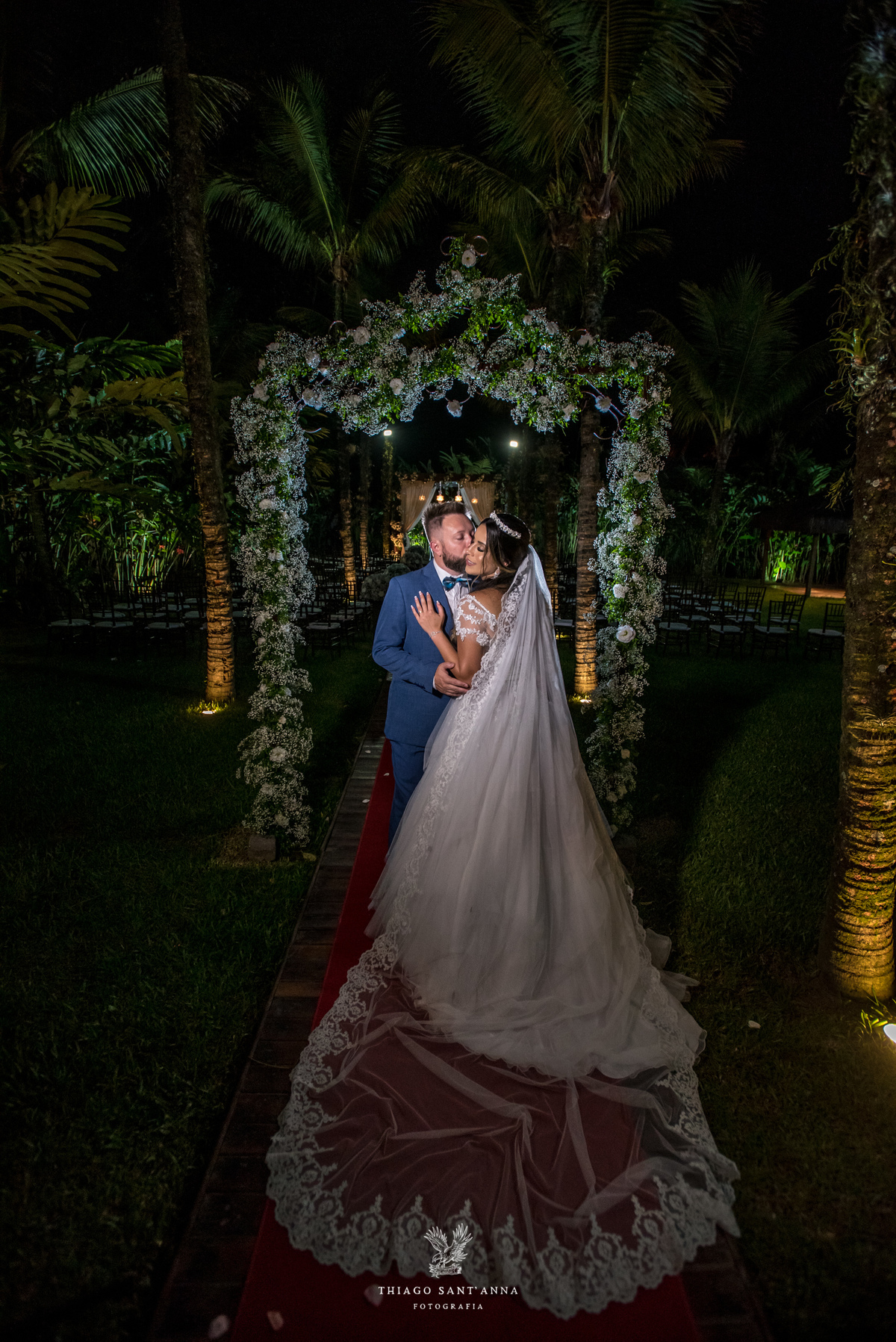 noivos se abraçam ambiente externo vegetação flores brancas noivo terno azul noiva vestido renda 