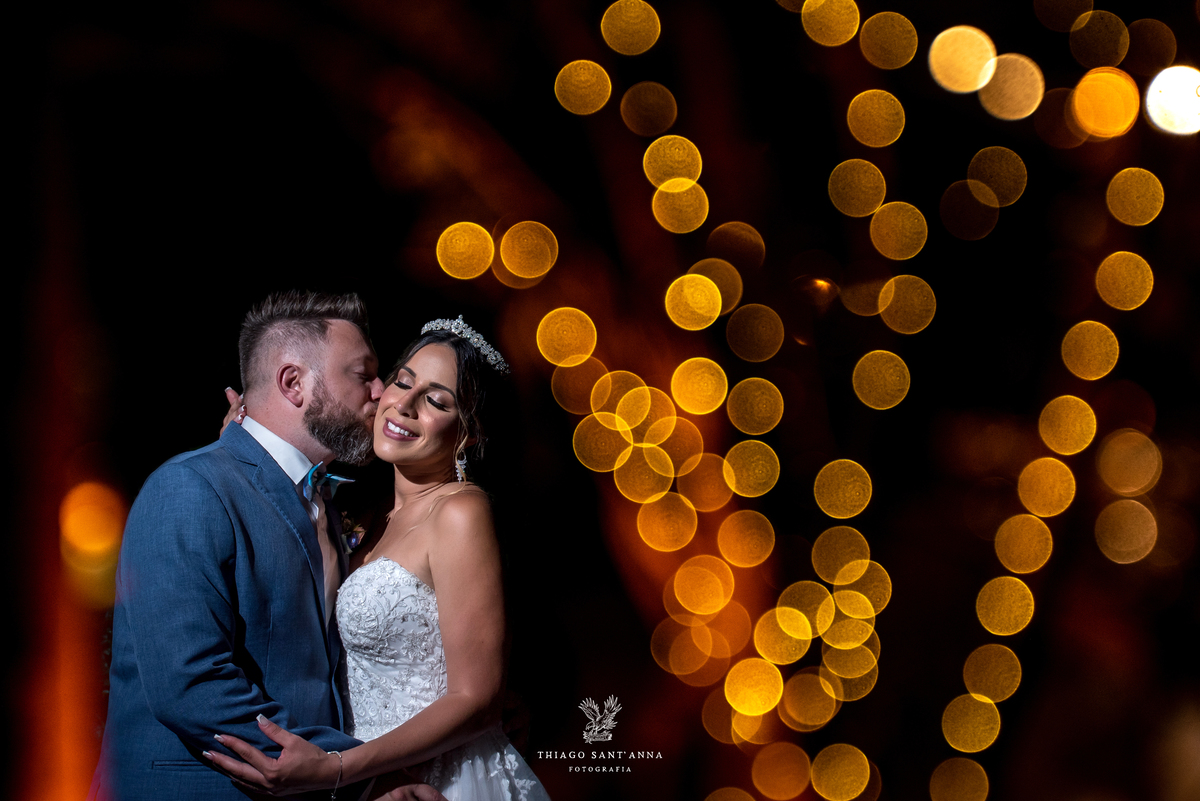 noiva beija rosto noiva luzes laranja ao fundo