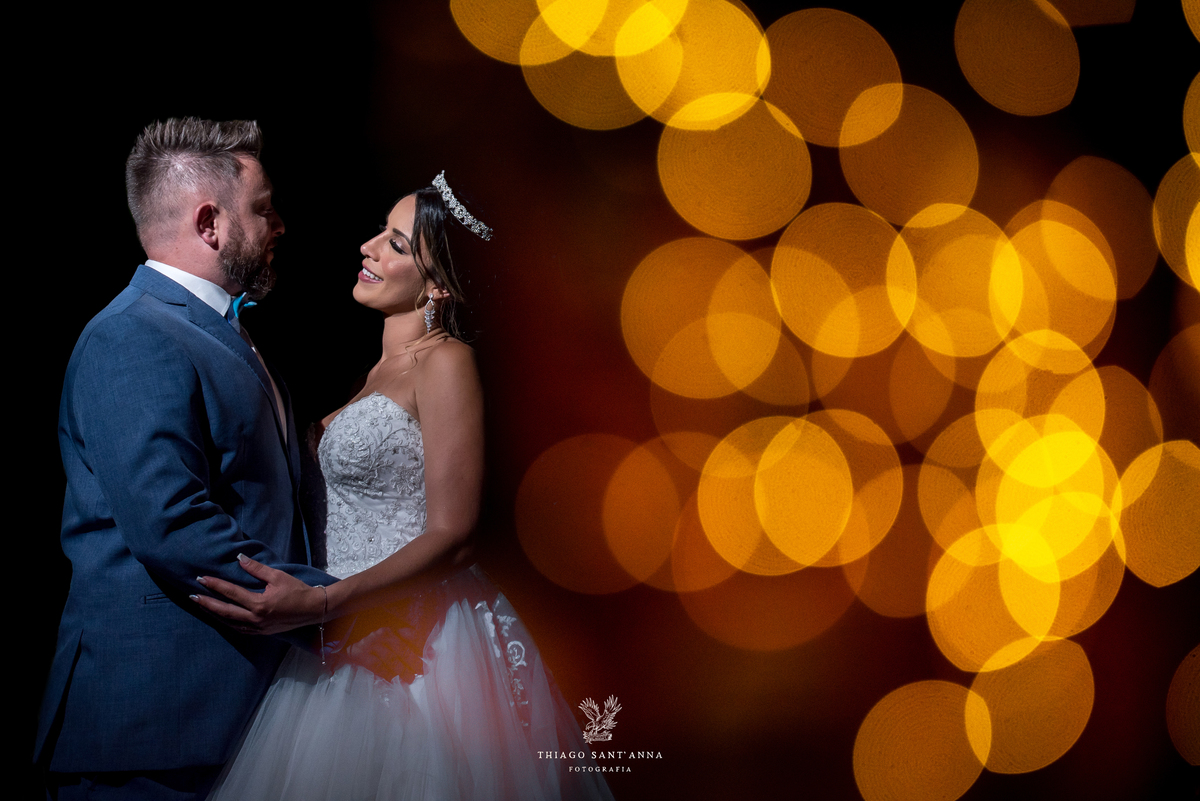 noivos se observam  luzes laranja ao fundo