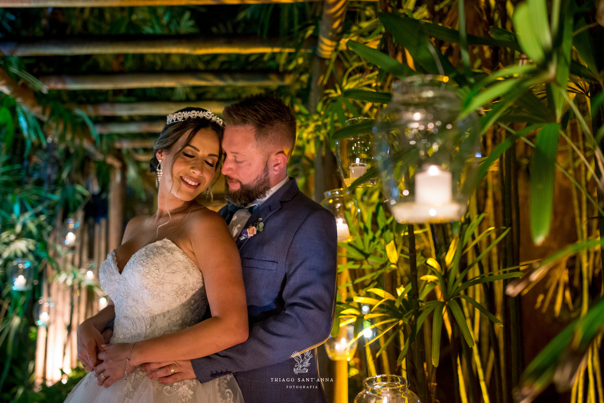 noivos se abraçam noiva sorri caminho bambu vegetação velas