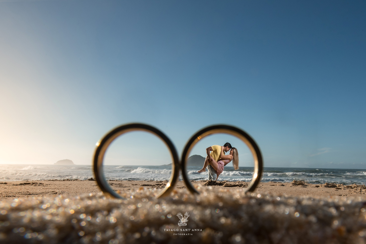 ensaio casal paisagem praia através das alianças
