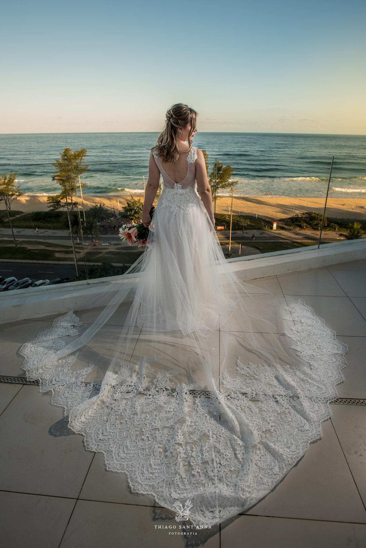 noiva vestido véu buque flores tons de rosa paisagem praia
