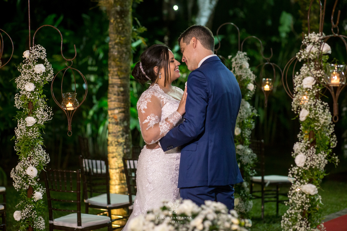 noivos abraçados se observam decoração flores brancas