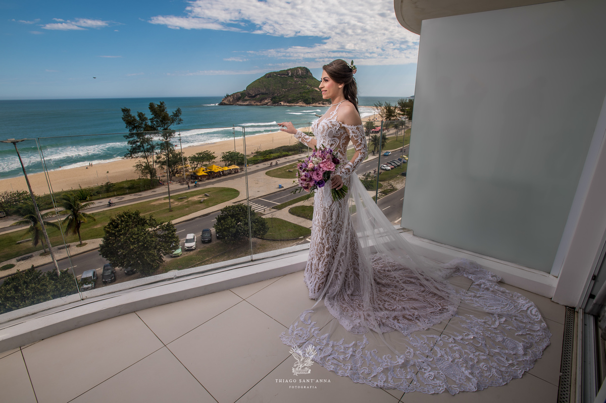 noiva observa paisagem praia vestido renda véu 