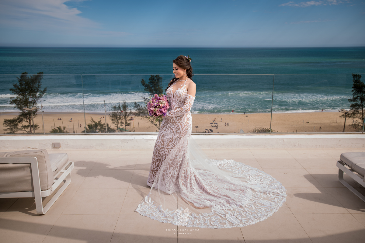 noiva observa paisagem praia vestido renda véu 