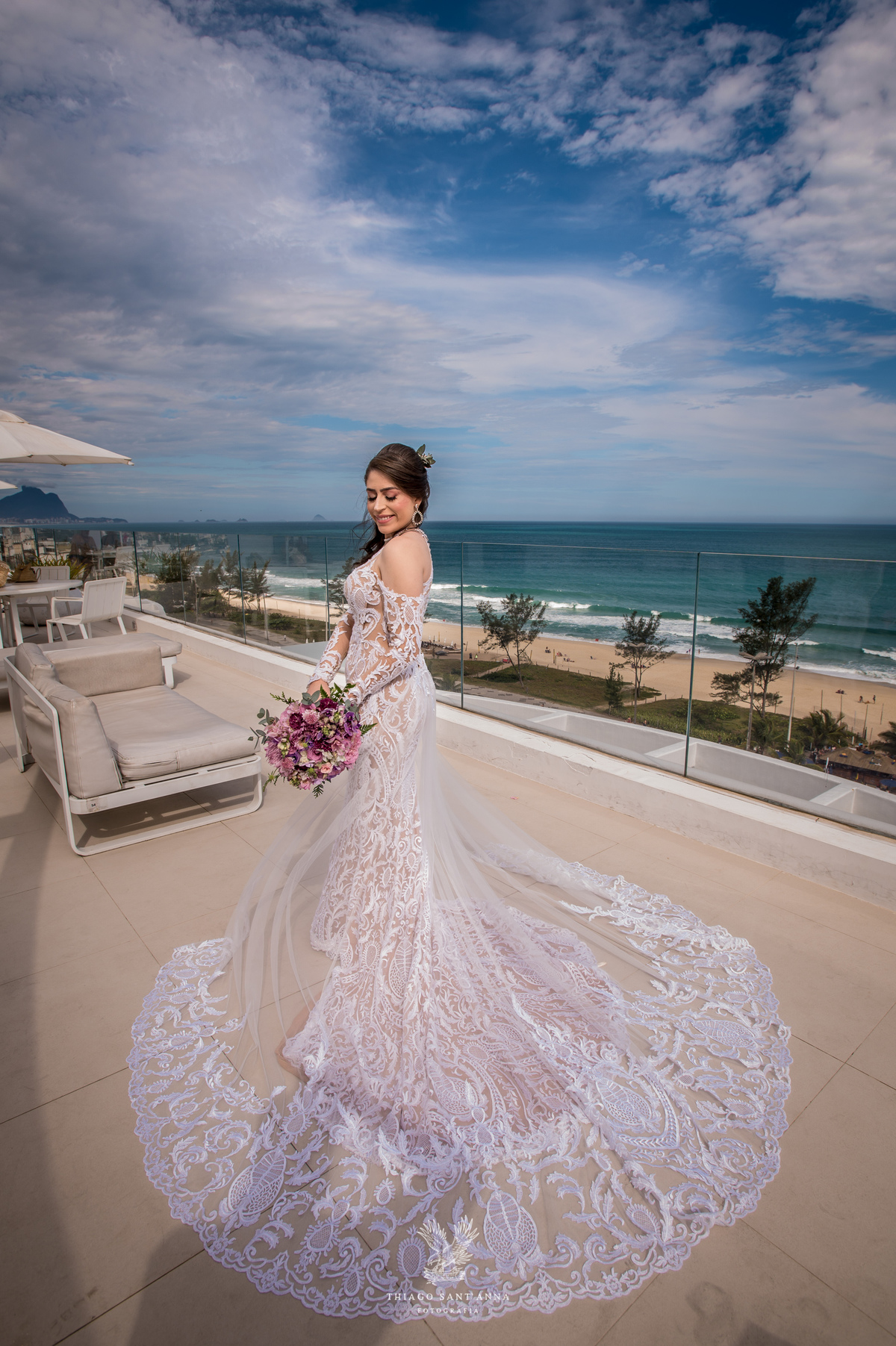 noiva observa paisagem praia vestido renda véu 