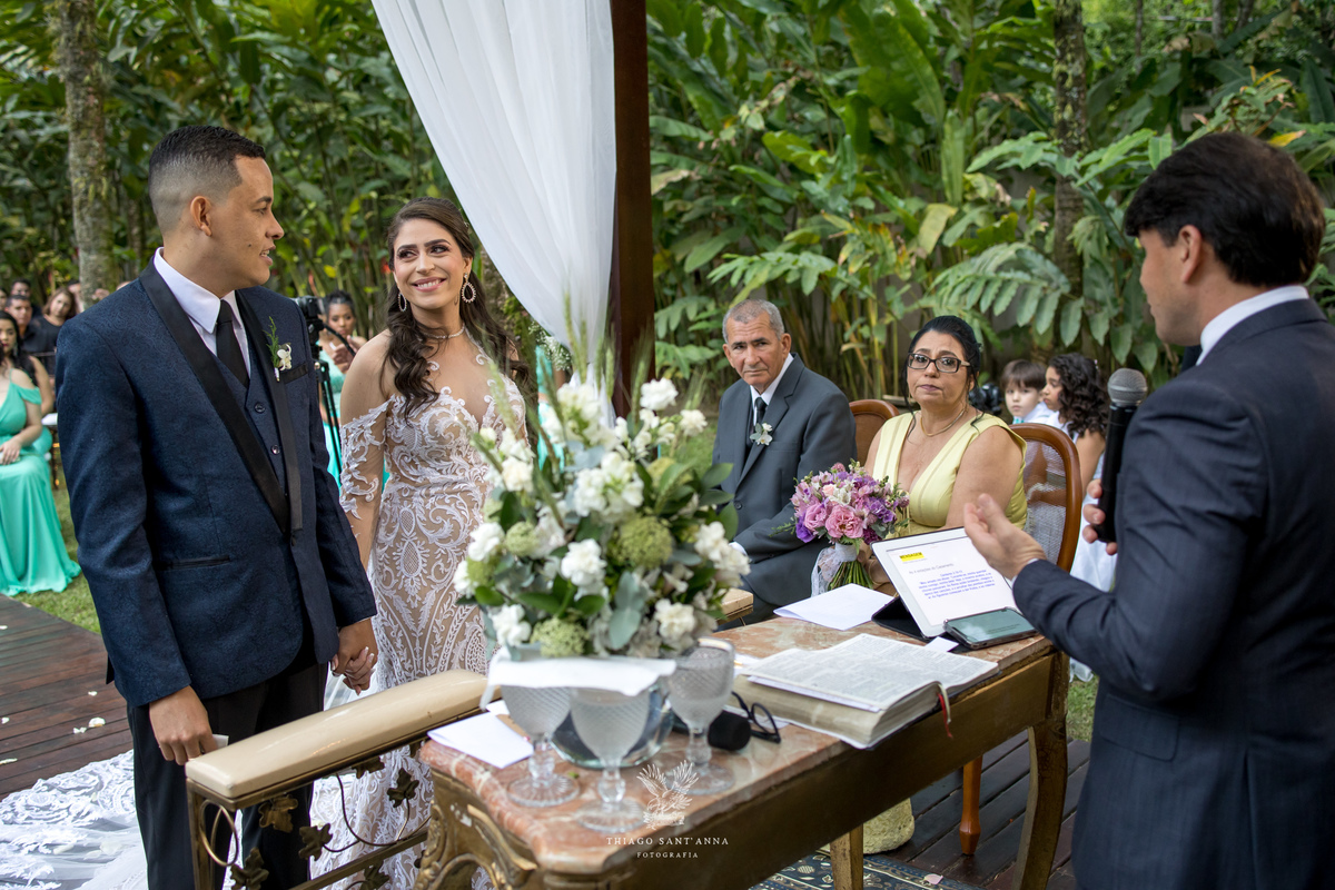 noivos no altar sorrindo se admiram estrutura de madeira tecido branco 