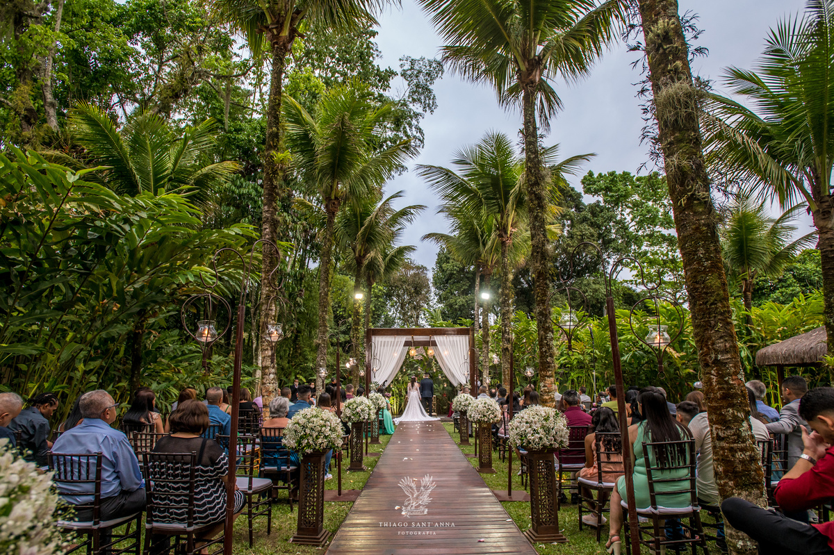 noivos no altar convidados observam decoração flores brancas ambiente externo vegetação gramado 