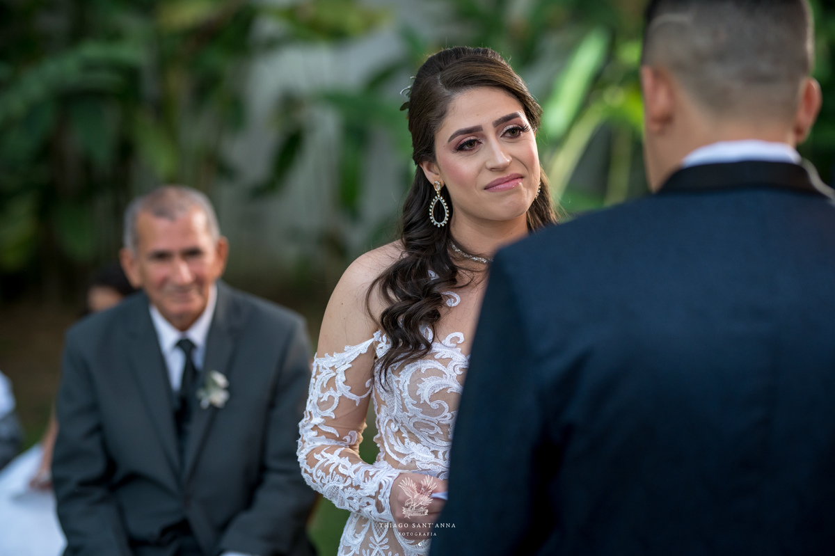 noivos no altar noiva emocionada familiar ao fundo vegetação folhas