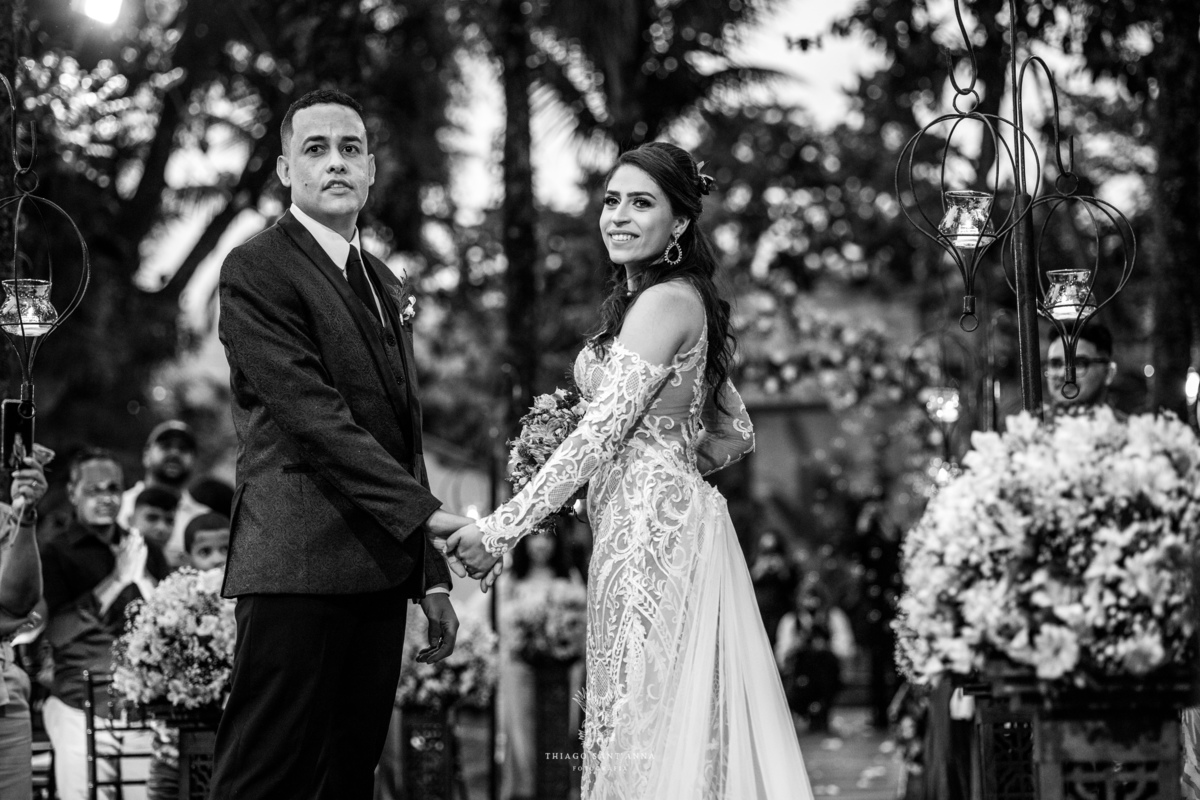 noivos sorrindo de mãos dadas no altar preto e branco
