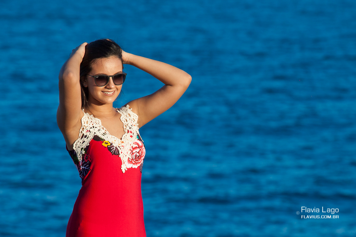 A debutante segurando seu cabelo posa para seu ensaio de 15 anos na praia pela fotógrafa de debutantes Flavia Lago no Rio de Janeiro - RJ
