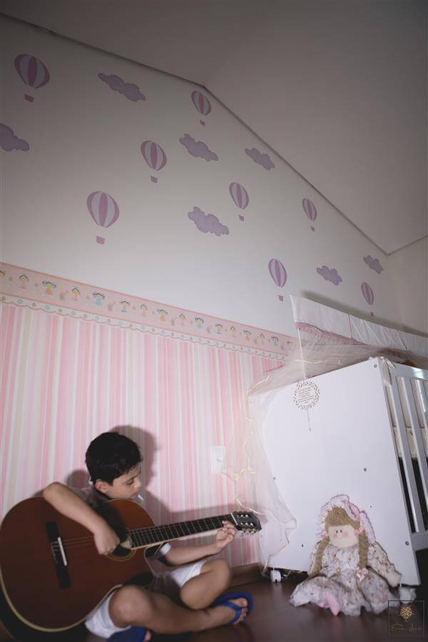 Filho tocando violão no quarto da futura irmã. Foto de ensaio gestante da fotógrafa Érica Dias.