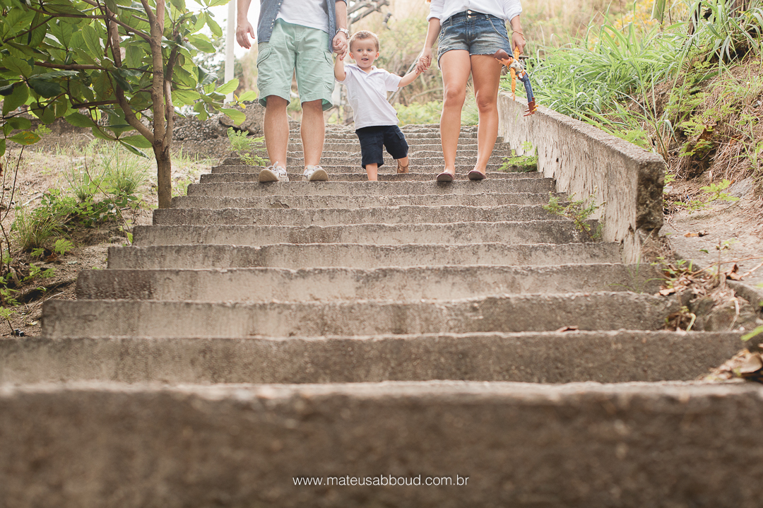 família, pai, mãe e filho. os três descendo uma escada, todos de mãos dadas sendo o filho no meio, dando uma mão para o pai e outra para a mãe.