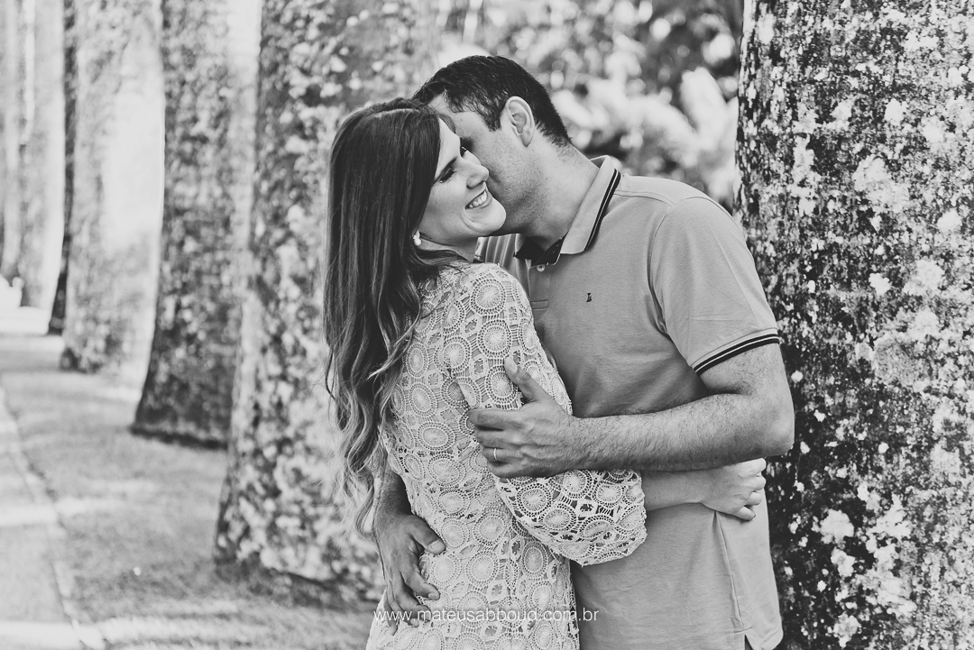 foto em preto e branco do noivo beijando a noiva e a noiva sorrindo no jardim botânico no rio de janeiro