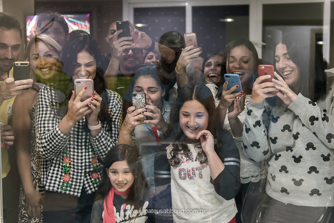 Família admirando através do vidro o bebê no bercário.