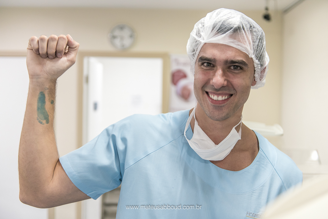 Pai com a marca do pé do bebê no braço após o bebê fazer exame do pezinho.